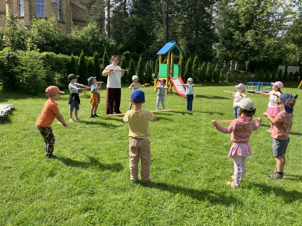 Dzieci i wychowawczyni podczas zajęć ruchowych w ogrodzie przedszkola